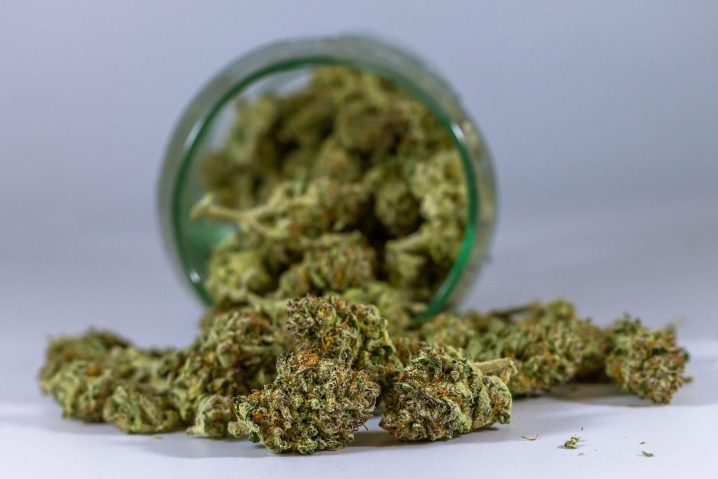 High-quality close-up of cannabis buds spilling from a glass jar.
